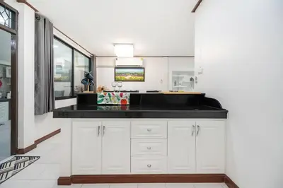 a kitchen with white cabinets and a black counter top at MIQ HK16 - 3BR Huai Khwang MRT with Pool Table near Jodd Fair in Ban Zong Katiam