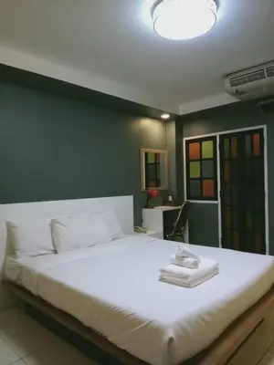 a bedroom with a white bed with a green wall at Bangkok Travel Suites Hotel in Nonthaburi