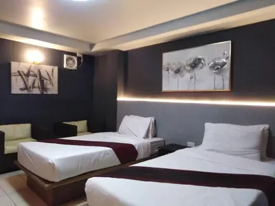 a hotel room with two beds and a couch at Bangkok Travel Suites Hotel in Nonthaburi