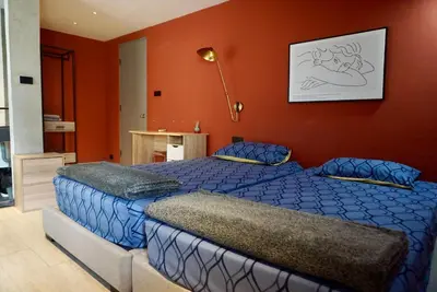 a bedroom with two beds and an orange wall at Silom Soi 3 Hash Apartment hip and funky with rooftop view in Bangkok