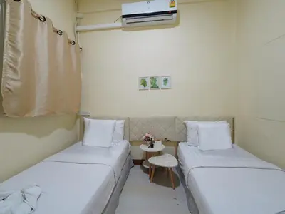 a small room with two beds and a table at EZ Sleep @ Ratchada 19 in Bangkok