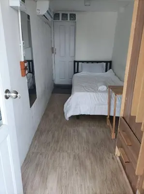 a small bedroom with a bed and a table at Chubby 9 single room in Bangkok