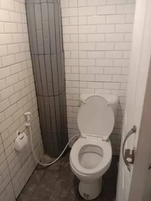a small bathroom with a toilet and a shower at Chubby 9 single room in Bangkok
