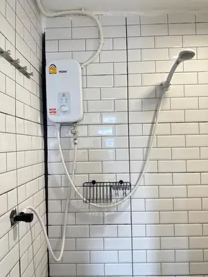 a white tiled bathroom with a shower head at Chubby 9 single room in Bangkok