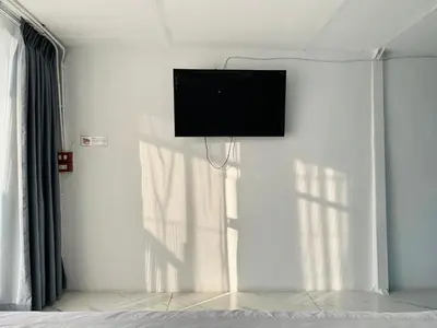 a flat screen tv on a white wall in a bedroom at Chubby 9 in Bang O