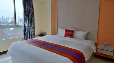 a bedroom with a large bed with a window at Aryan Suites Hotel in Bangkok