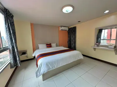 a bedroom with a bed in a room with windows at Aryan Suites Hotel in Bangkok