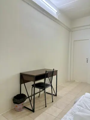 a table and a chair in a room with a bed at Suppamas Mansion ศุภมาส แมนชั่น in Bangkok Yai