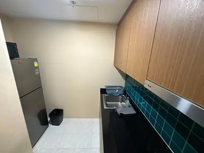 a small kitchen with a sink and wooden cabinets at 2bd Apartment near icon Siam close to Everything in Bangkok