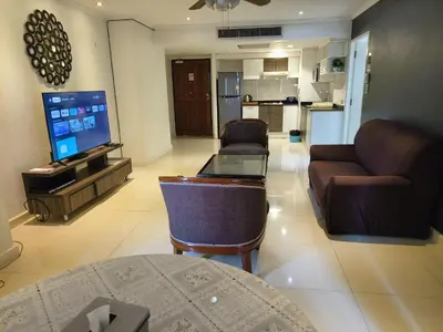 a living room with a couch and a tv at Fully Furnished Omni Tower Apartments Nana - Sukhumvit soi 4 in Bangkok