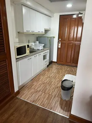 a kitchen with white cabinets and a wooden floor at Fully Furnished Omni Tower Apartments Nana - Sukhumvit soi 4 in Bangkok