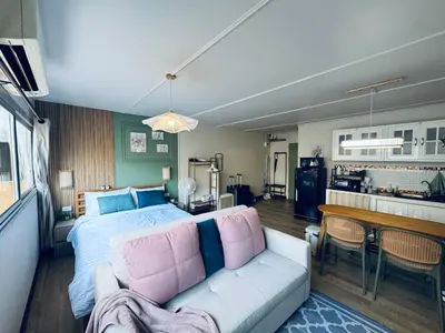 a bedroom with a bed and a table and a kitchen at IMPACT challenger ห้องพักรายวัน เมืองทองธานี ตึก C9, P2, P1 每日房 in Nonthaburi