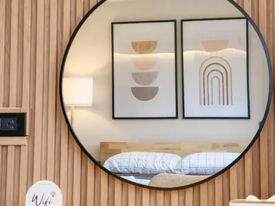 a mirror in a room with a bed and framed pictures at Better Room ห้องพักรายวัน เมืองทองธานี C4 in Ban Bang Phang