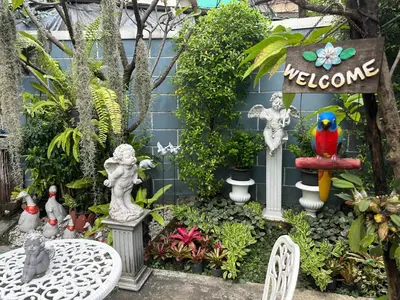a garden with statues and plants and a table at Baanfahsai in Makkasan
