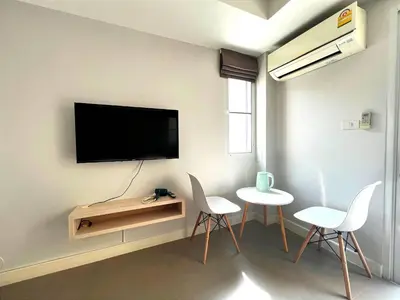 a living room with two chairs and a tv on a wall at XX Mitr Inn The Grand Palace - Mrt Samyot Station มิตร อินน์ พระบรมมหาราชวัง in Bangkok