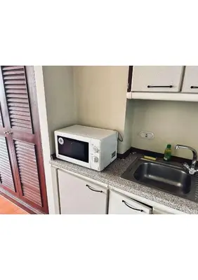 a small kitchen with a microwave and a sink at Affordable Serviced Apartment Nana - Omni Tower Sukhumvit location in Bangkok