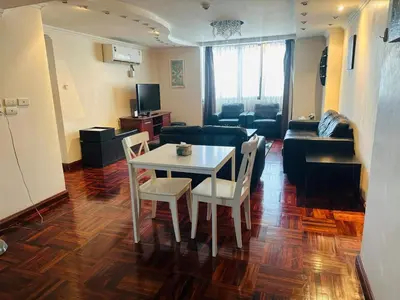 a living room with a table and chairs and a couch at Affordable Serviced Apartment Nana - Omni Tower Sukhumvit location in Bangkok