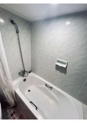 a white bath tub in a bathroom with a shower at Affordable Serviced Apartment Nana - Omni Tower Sukhumvit location in Bangkok