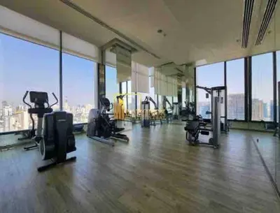 a gym with cardio equipment in a large room with windows at Ultimate Luxurious in Prime Bangkok Asoke in Bangkok