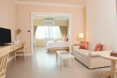 a hotel room with a bed and a living room at The Raya Surawong Bangkok in Bangkok