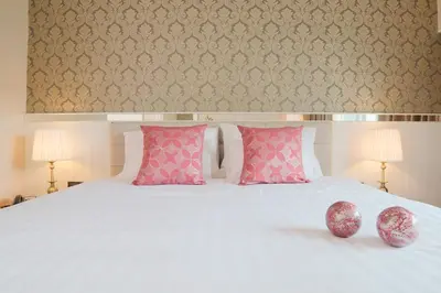 a bedroom with a white bed with pink pillows at The Raya Surawong Bangkok in Bangkok