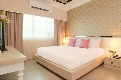 a bedroom with a large white bed with pink pillows at The Raya Surawong Bangkok in Bangkok