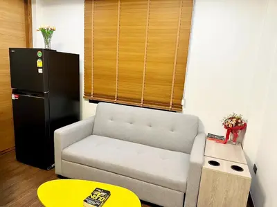a living room with a couch and a black refrigerator at Arun Heaven Bangkok in Bangkok Noi