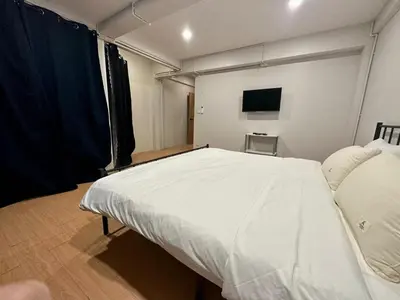 a bedroom with a large white bed and a tv at The Cute Silom hostel in Bangkok