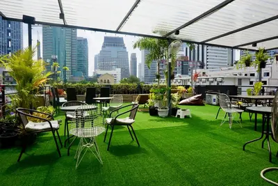 a patio with green grass and tables and chairs at Hash Silom Apartment @ Silom Soi 3 in Bangkok