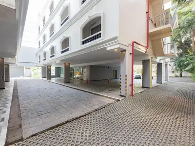 an empty courtyard of a white building with a sidewalk at Romance Hotel Srinakarin in Bangkok