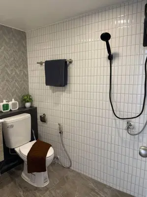 a white tiled bathroom with a toilet and a shower at Private house with Pagoda view, near Grand Palace in Bangkok