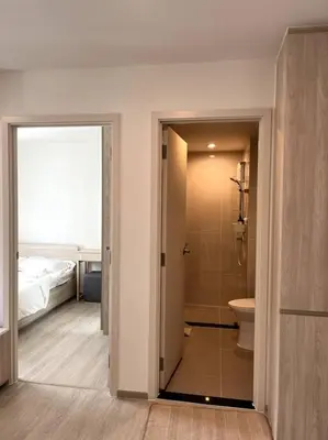 a bathroom with a shower and a toilet and a bed at Nue Z-Square Suan Luang Station - Cozy 2BR Condo, Pool&Gym, Near Suan Luang Station in Bangna