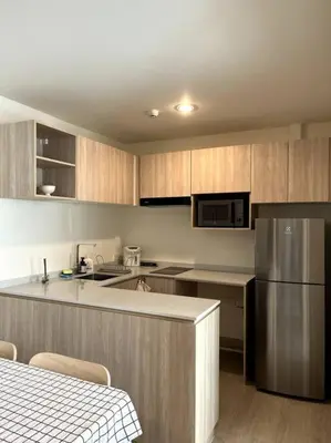 a kitchen with wooden cabinets and a stainless steel refrigerator at Nue Z-Square Suan Luang Station - Cozy 2BR Condo, Pool&Gym, Near Suan Luang Station in Bangna