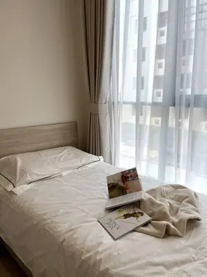 a bed with a book on it with a window at Nue Z-Square Suan Luang Station - Cozy 2BR Condo, Pool&Gym, Near Suan Luang Station in Bangna