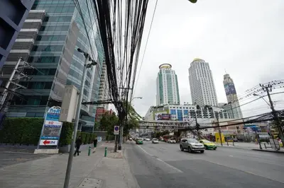 a city street with cars driving down a street with tall buildings at The Bangkok Venice Suite in Bangkok