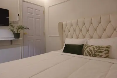 a bedroom with a large white bed with a large headboard at AboutTime Bangkok in Bangkok