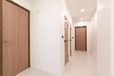 a hallway with white walls and wooden doors at Townhouse in Pratunam Bangkok in Bangkok