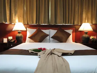 a bed with two lamps and a dress on it at The Grand Sathorn in Bangkok