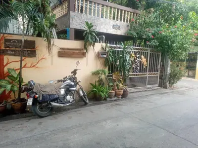 a motorcycle parked next to a building with plants at GN GOOD NICE in Bangkok