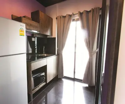 a small kitchen with a refrigerator and a window at Varrzon Residence Srinakarin 56 in Bangna