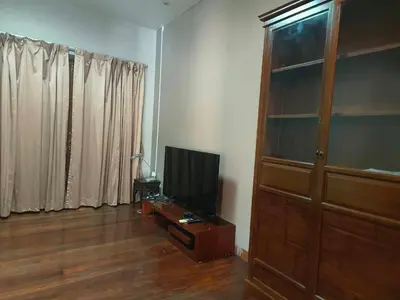 a living room with a tv and a wooden cabinet at Tanwa Suite - MRT Ratchadapisek in Bangkok