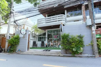 a white house with a clock on the side of it at 420 Hostel - Ekkamai Buds & Beds in Bangkok