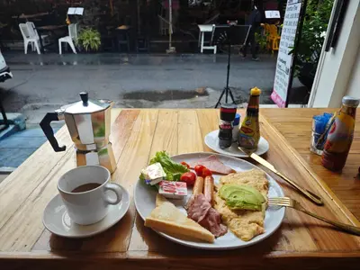 a table with a plate of food and a cup of coffee at Panda Lodge Home Stay in Bangkok