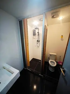 a small bathroom with a toilet and a shower at Panda Lodge Home Stay in Bangkok