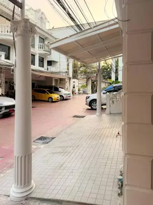 a building with columns and cars parked in a parking lot at Private House 3 Suite Beds + Double Beds in Heart of Phromphong in Bangkok