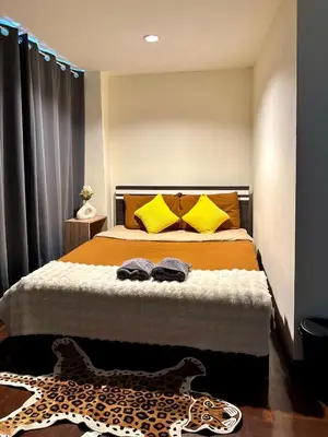 a bedroom with a bed with yellow pillows and a leopard rug at Private House 3 Suite Beds + Double Beds in Heart of Phromphong in Bangkok