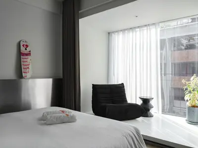 a bedroom with a bed and a chair next to a window at Stupid Stay in Bangkok