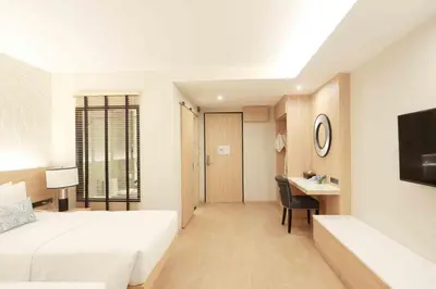 a bedroom with a bed and a desk and a television at Iconic Hotel in Bangkok