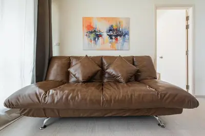 a brown leather couch sitting in a living room at 2BR, 6 Mins walk BTS Wuttakat in Bangkok