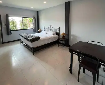 a bedroom with a bed and a table and a window at IMM Resort in Bangkok